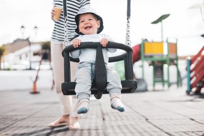A happy small child in a spacious swing, avoiding container baby syndrome through outdoor playtime