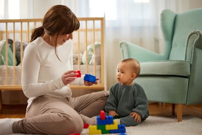 Toddler and their mother playing with colourful building blocks, improving fine motor skills.