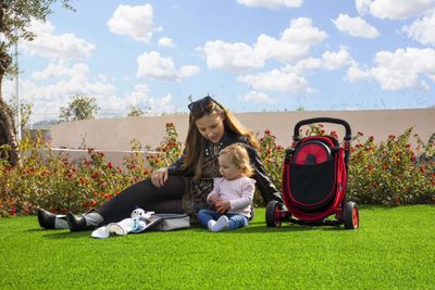 Mother sitting on the ground with her child next to a folded pushchair