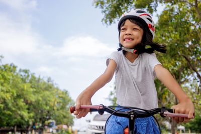 A little girl riding a bike with a helmet on.