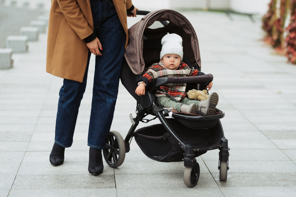 A woman pushing a stroller with a baby in it.