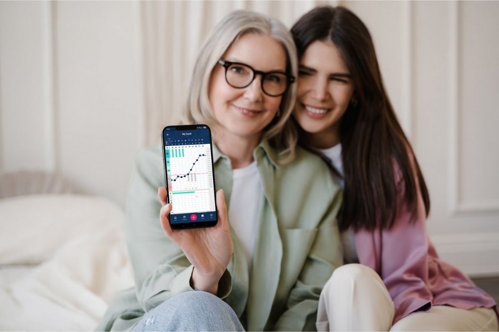 a couple of women sitting next to each other holding a cell phone