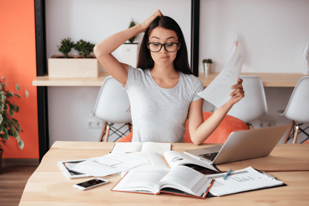 a woman sitting at a table with a laptop and papers in front of her
