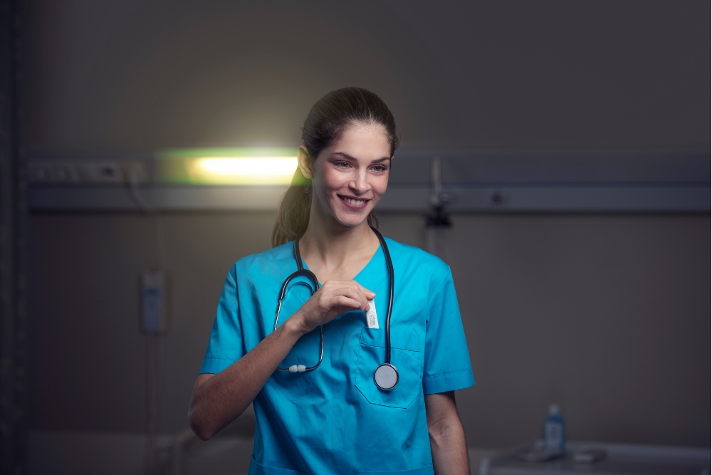 a woman in a blue scrub suit holding a stethoscope