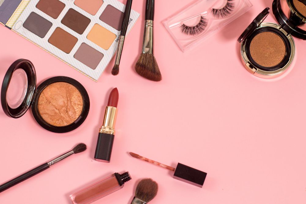 a pink background with cosmetics and eyeliners