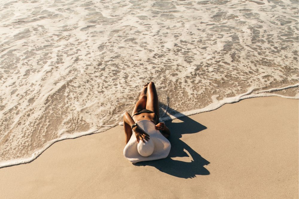 a woman laying on top of a beach next to the ocean