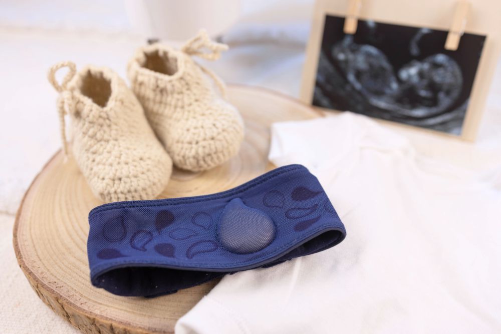 a pair of baby shoes sitting on top of a wooden slice