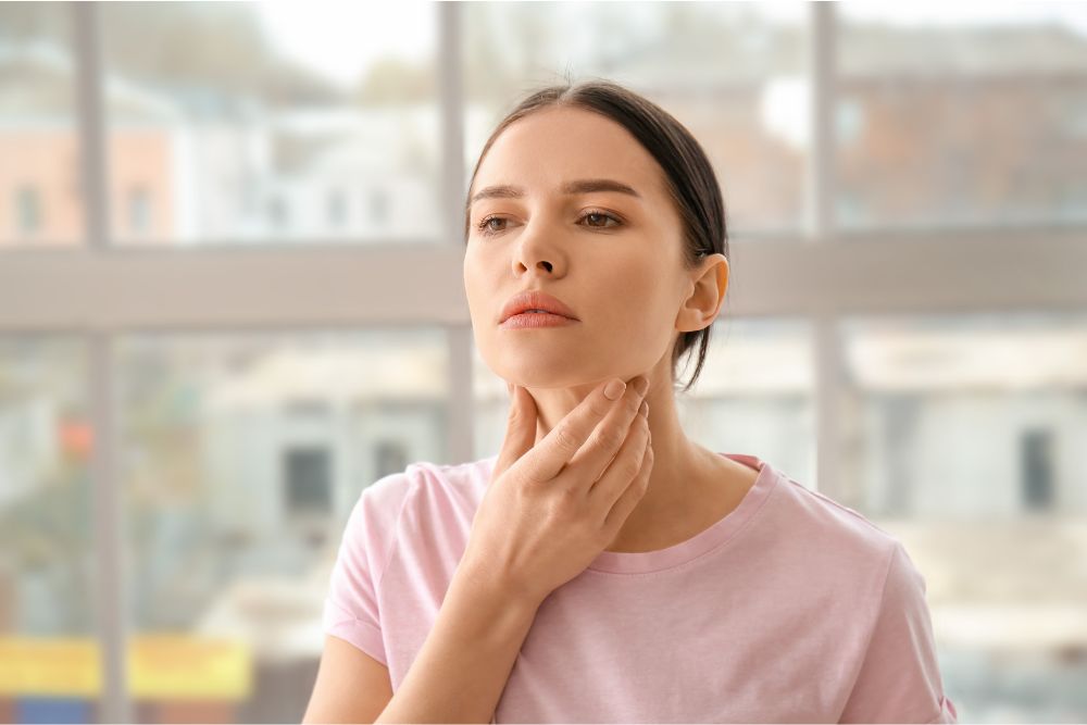 a woman in a pink shirt is holding her hand to her mouth