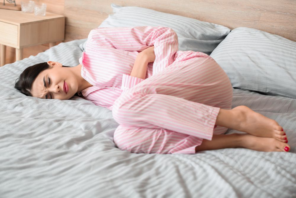 a woman laying on a bed in a pink striped pajamas