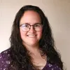 a woman wearing glasses and a purple shirt