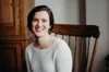 a woman sitting in a chair smiling at the camera