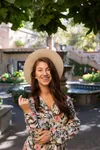 a woman wearing a hat standing under a tree