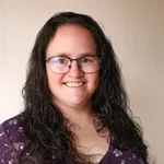a woman wearing glasses and a purple shirt
