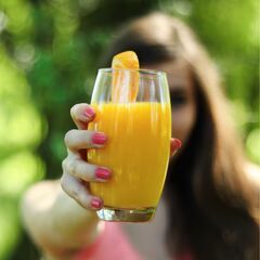 a woman holding a glass of orange juice