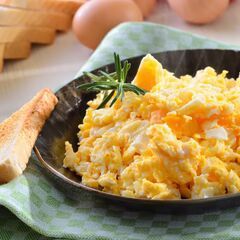 a plate of scrambled eggs and toast on a table