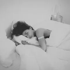 a woman laying in a bed with a white blanket