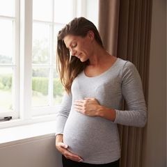 a pregnant woman standing in front of a window