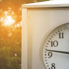 a close up of a clock with trees in the background