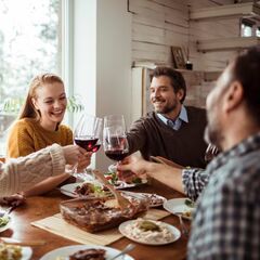 a group of people sitting around a table with food and wine