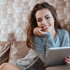 a woman sitting on a couch looking at a tablet