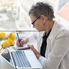 a woman sitting at a desk writing on a notebook