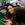 a woman smiles as she leans over a pile of vegetables