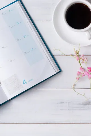 a cup of coffee and a planner on a white table