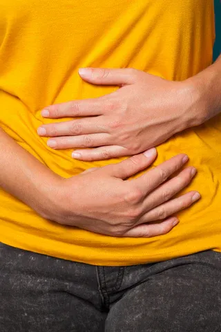 a woman in a yellow shirt holding her stomach