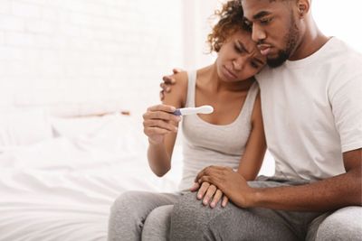 a man and woman sitting on a bed looking at a toothbrush