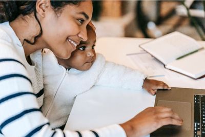 a woman and a child are looking at a laptop