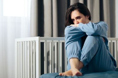 a woman sitting on top of a bed next to a crib