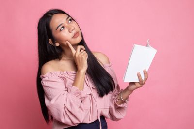 a woman in a pink shirt is holding a book