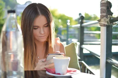 a woman sitting at a table looking at her cell phone