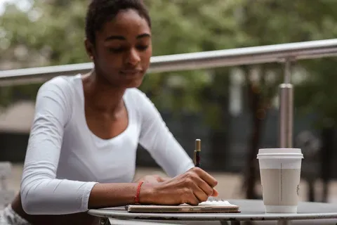 a woman sitting at a table writing on a piece of paper