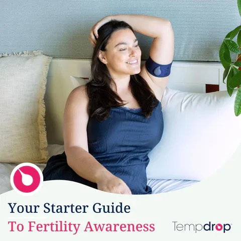 a woman sitting on top of a bed next to a plant