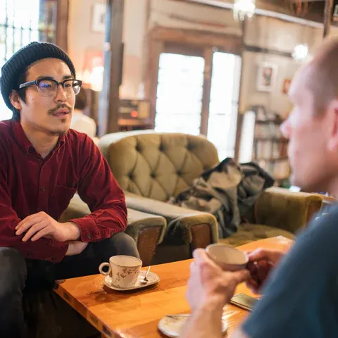 a man sitting at a table talking to another man