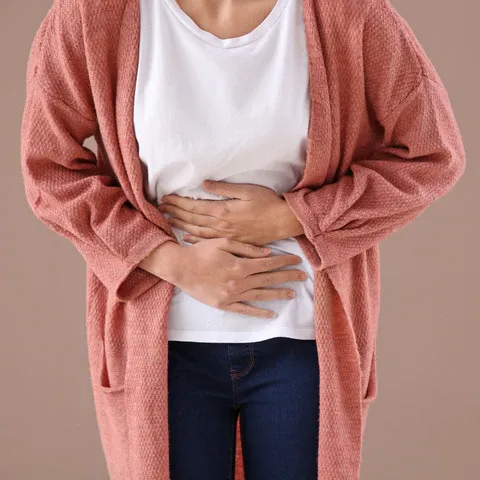 a woman holding her stomach while wearing a cardigan