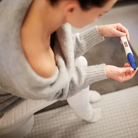 a woman is holding a pregnancy in her hand