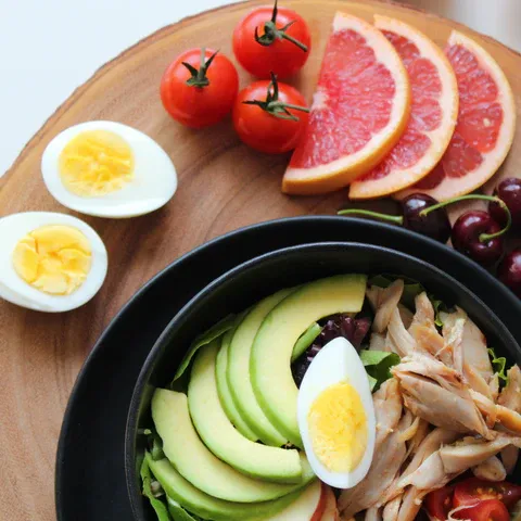 a bowl of salad with hard boiled eggs, tomatoes, avocado, and