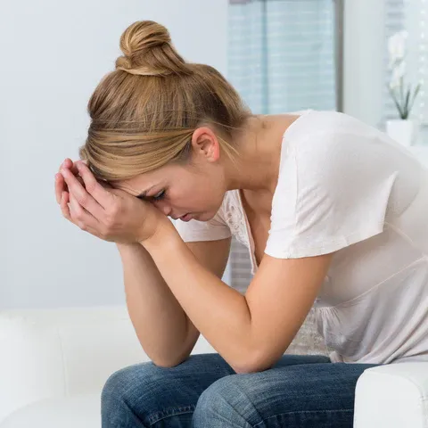 a woman sitting on a couch holding her head in her hands