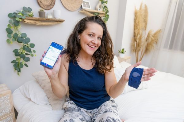 a woman sitting on a bed holding a cell phone