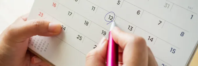 a person writing on a calendar with a pen