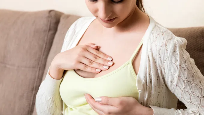 a woman holding her breast while sitting on a couch