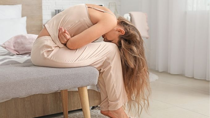 a woman sitting on a bed with her head down