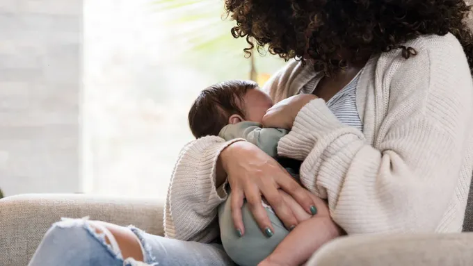 a woman sitting on a couch holding a baby