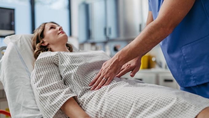 a woman laying in a hospital bed being assisted by a nurse