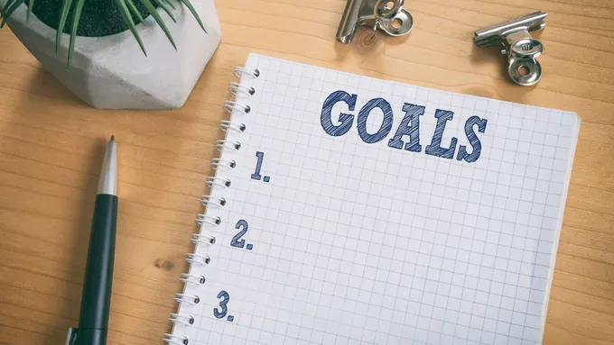 a notepad with the word goals written on it next to a pen 