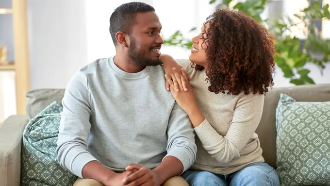 a man and woman sitting on a couch looking at each other