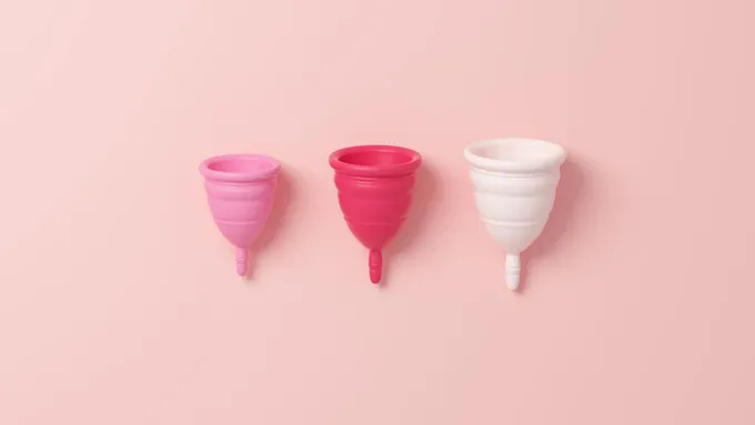 three plastic cups lined up on a pink background