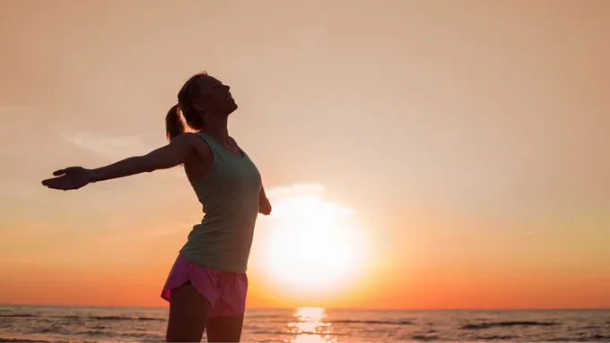 a woman standing on a beach at sunset